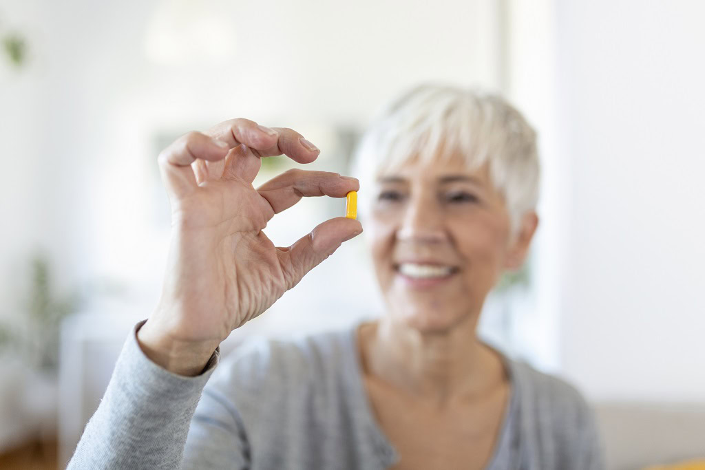 senior-woman-home-sitting-table-kitchen-home-holding-cup-water-pill